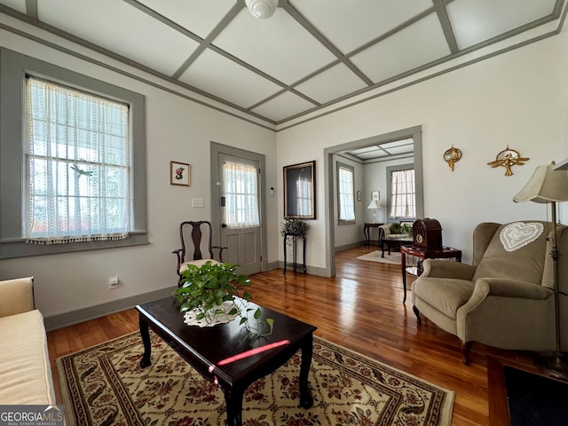 living room featuring coffered ceiling, baseboards, and wood finished floors