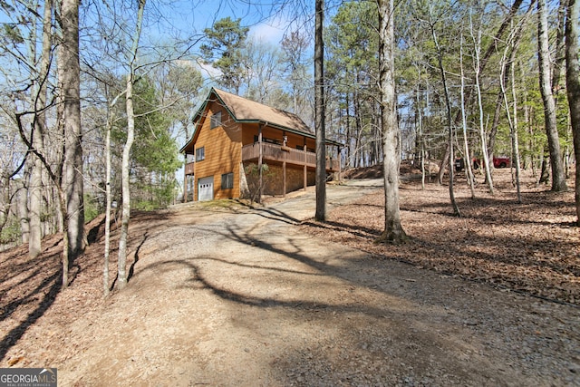 view of side of home featuring an attached garage and dirt driveway