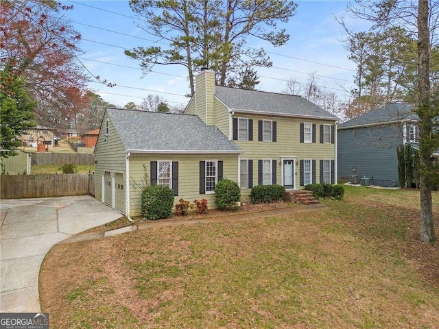 colonial inspired home with roof with shingles, concrete driveway, a front yard, fence, and a garage