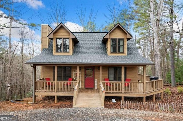 view of front of house featuring covered porch, a shingled roof, and a chimney