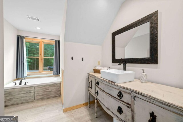 full bathroom featuring a garden tub, recessed lighting, vanity, visible vents, and vaulted ceiling