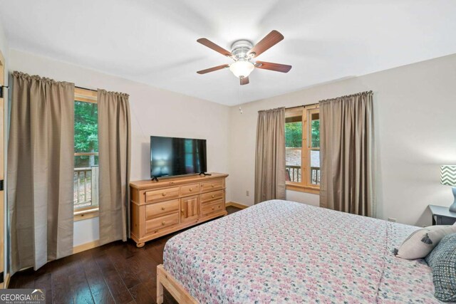 bedroom featuring dark wood-style floors, ceiling fan, multiple windows, and baseboards