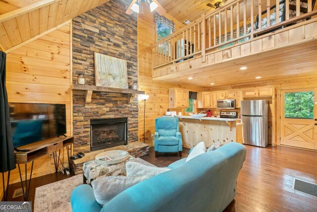 living room featuring wooden ceiling, wood walls, visible vents, and wood finished floors