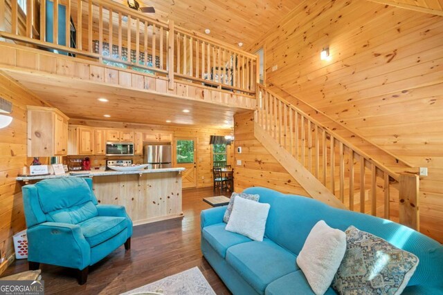 living room featuring wooden ceiling, a high ceiling, wood walls, stairway, and dark wood-style floors