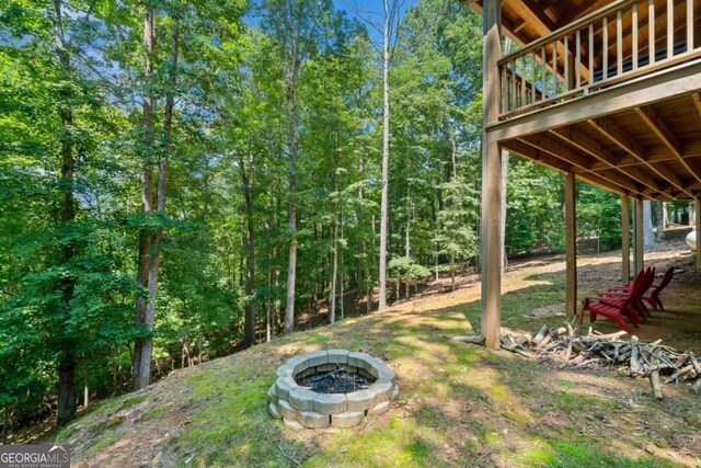 view of yard with an outdoor fire pit and a wooded view