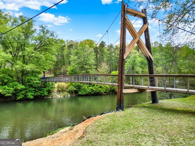 dock area featuring a water view, a view of trees, and a yard