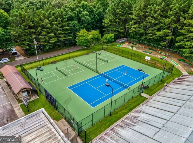 view of tennis court with fence and a lawn