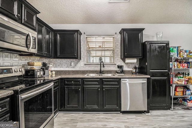 kitchen featuring a sink, appliances with stainless steel finishes, and dark cabinetry