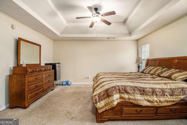 bedroom with light carpet, a tray ceiling, visible vents, and baseboards