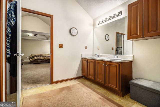 ensuite bathroom featuring lofted ceiling, a sink, a textured ceiling, and ensuite bath