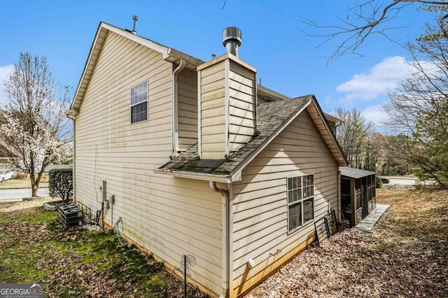 view of side of home with a shingled roof and a chimney