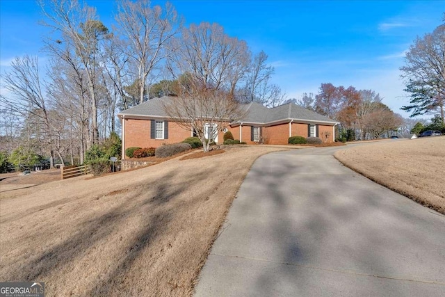 ranch-style house with driveway, fence, and brick siding