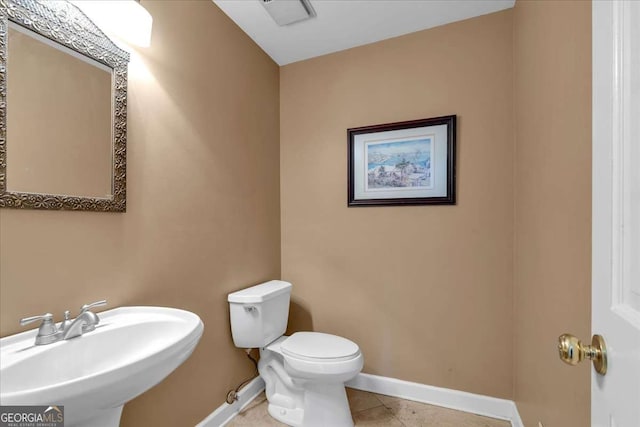 bathroom featuring tile patterned flooring, baseboards, a sink, and toilet