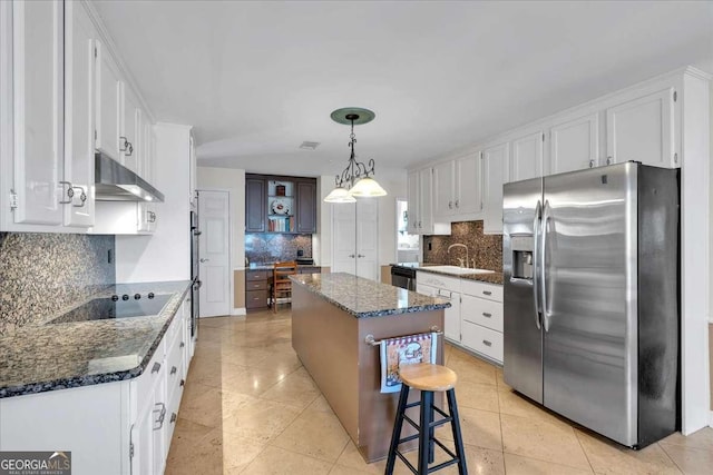 kitchen featuring white cabinets, a kitchen island, stainless steel appliances, under cabinet range hood, and a sink