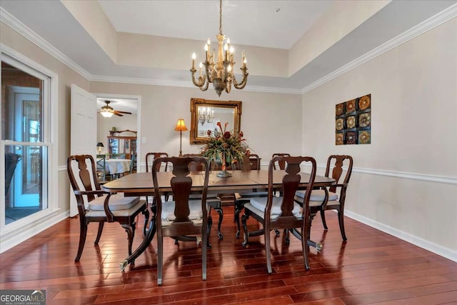 dining space featuring baseboards, a raised ceiling, and dark wood finished floors