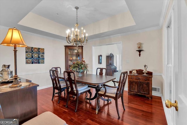 dining area featuring dark wood-style floors, a raised ceiling, visible vents, ornamental molding, and baseboards