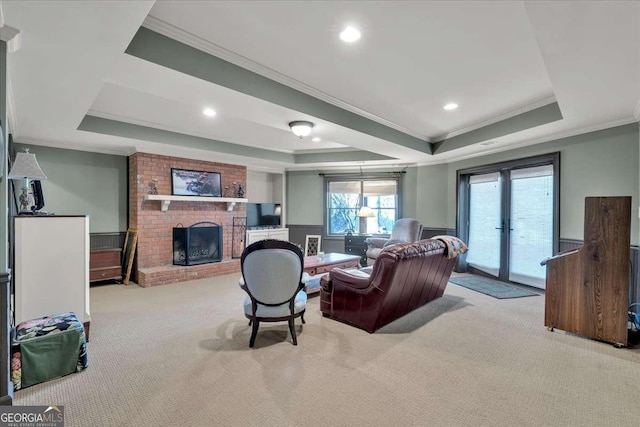 living area with a wainscoted wall, a fireplace, a raised ceiling, and carpet