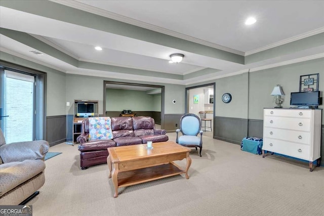 living area featuring carpet, a raised ceiling, wainscoting, and crown molding