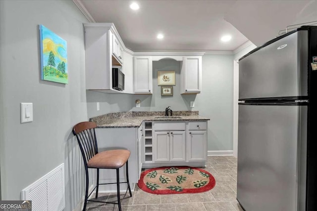 kitchen with black microwave, a sink, visible vents, white cabinetry, and freestanding refrigerator