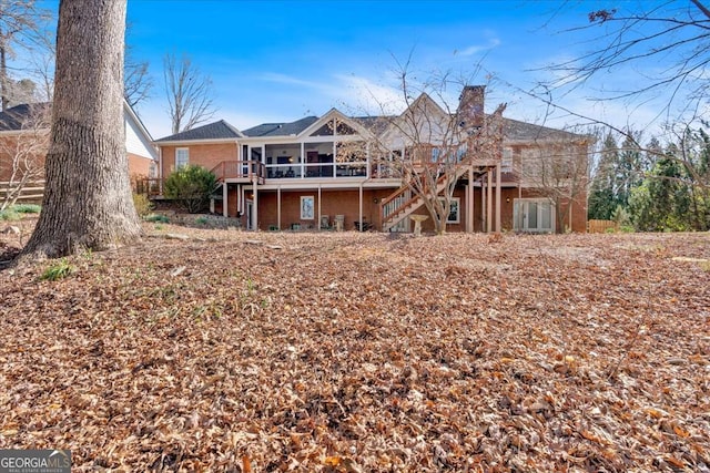 rear view of house with brick siding, a chimney, stairway, and a wooden deck