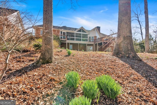 back of property with stairs and a sunroom