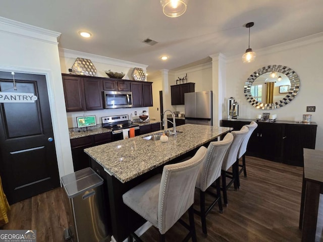 kitchen featuring visible vents, a breakfast bar, dark wood-type flooring, stainless steel appliances, and a sink