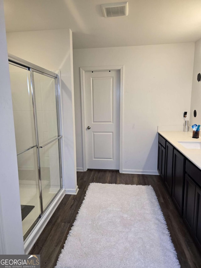 bathroom featuring visible vents, a shower stall, vanity, wood finished floors, and baseboards