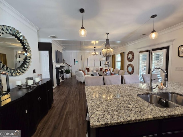 living area with dark wood-style flooring, coffered ceiling, a notable chandelier, and stairs