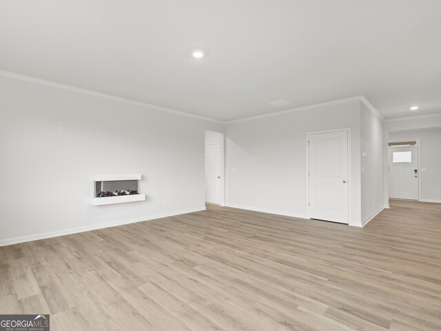 unfurnished living room featuring ornamental molding, light wood-type flooring, and baseboards