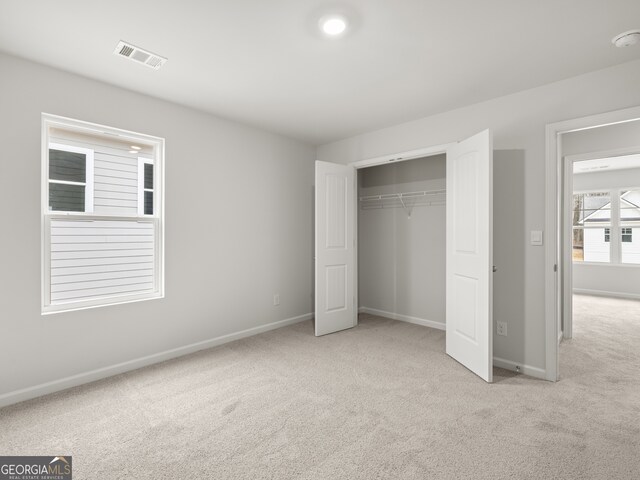 unfurnished bedroom with a closet, carpet flooring, visible vents, and baseboards