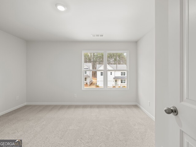 empty room featuring carpet, visible vents, and baseboards