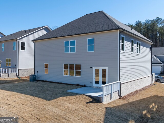 back of property with roof with shingles, french doors, central AC, and a patio