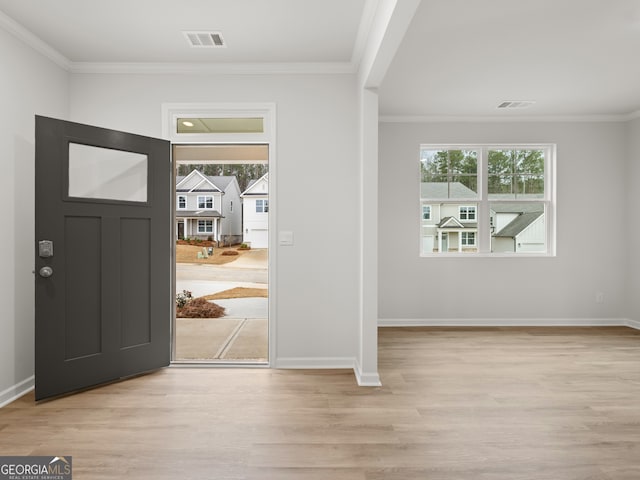 entrance foyer featuring a healthy amount of sunlight, light wood-style flooring, visible vents, and ornamental molding