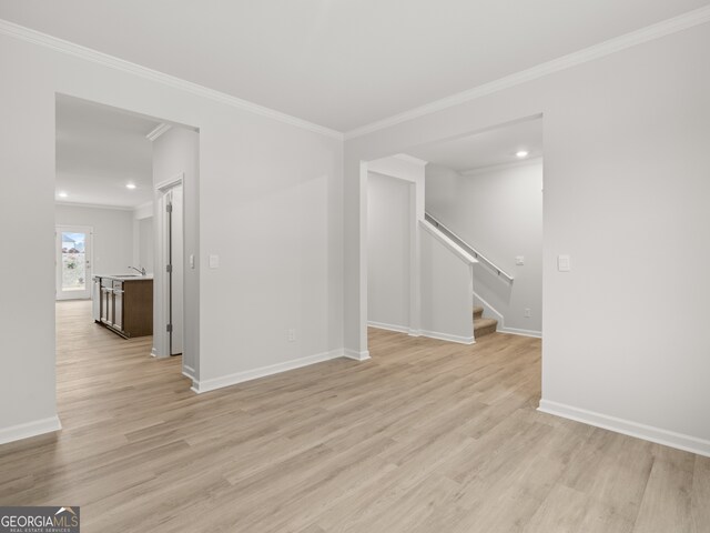 interior space with ornamental molding, baseboards, stairway, and light wood finished floors