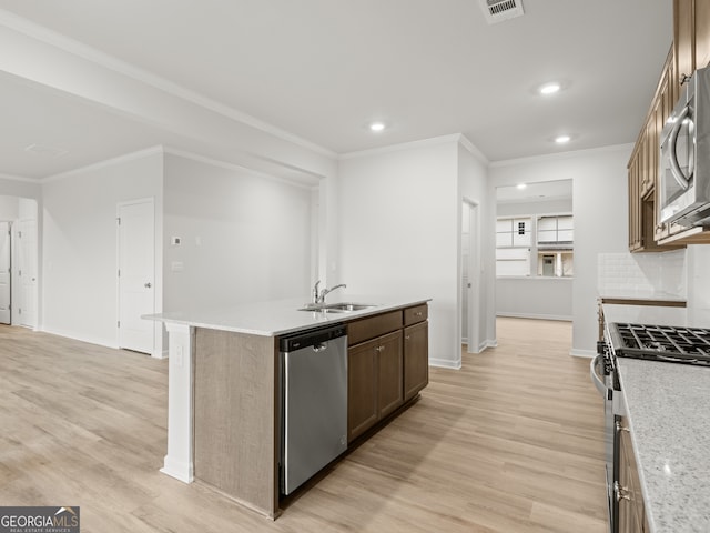 kitchen featuring stainless steel appliances, light wood-style floors, a sink, and backsplash