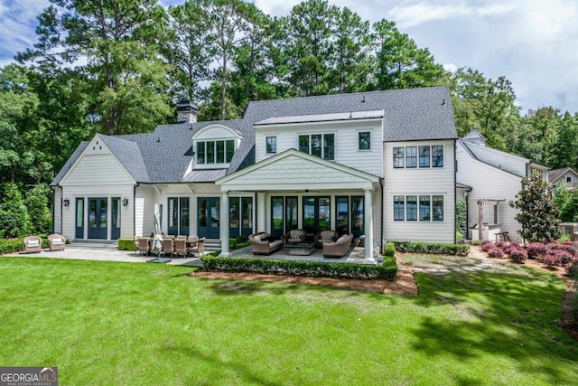 back of property featuring a chimney, an outdoor living space, a lawn, and a patio