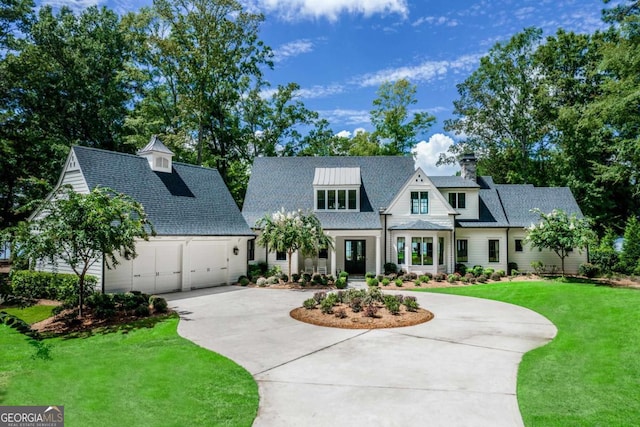 view of front of property with a garage, curved driveway, and a front lawn