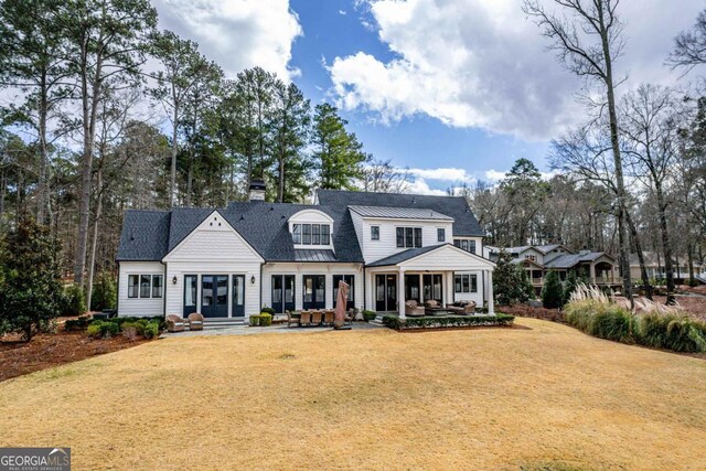 rear view of property with entry steps, a patio area, a lawn, and a chimney