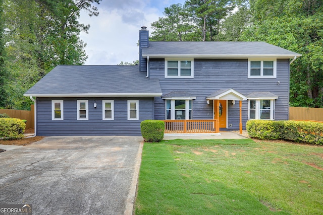 view of front of house with a front lawn, a chimney, and fence