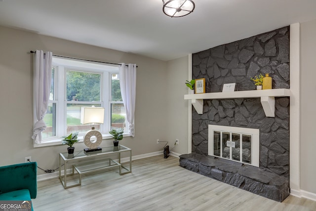 living area with a fireplace, baseboards, and wood finished floors