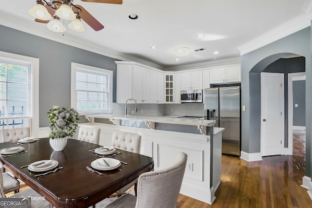 484 Martin St SE, Atlanta, GA 30312 - kitchen with a peninsula, arched walkways, glass insert cabinets, appliances with stainless steel finishes, and crown molding
