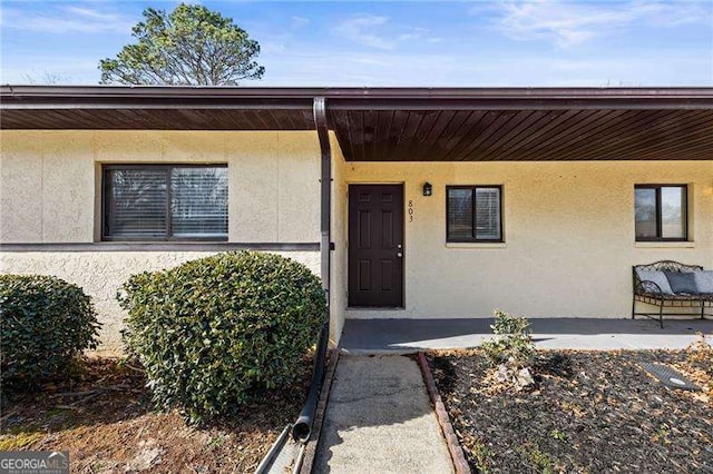 entrance to property with a patio area and stucco siding