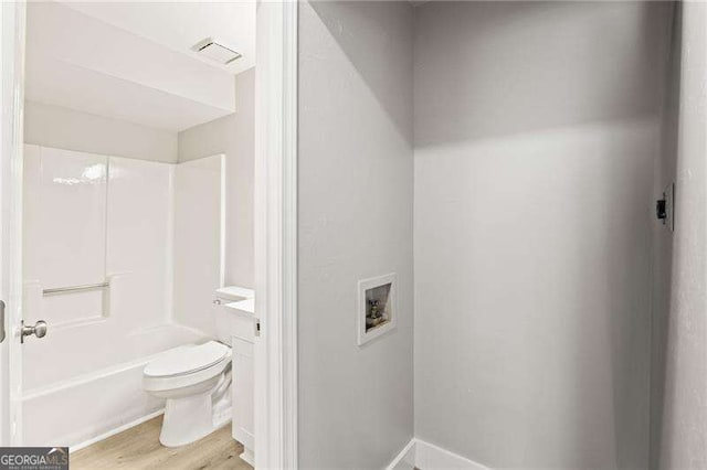 full bathroom with toilet, wood finished floors, visible vents, vanity, and tub / shower combination