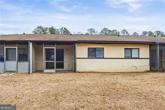 back of property featuring a sunroom and stucco siding