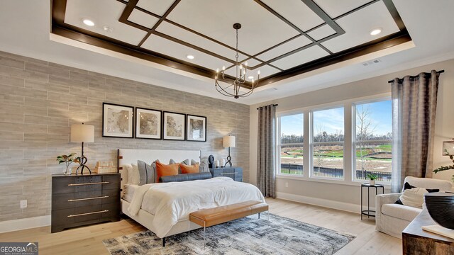 bedroom featuring light wood-style floors, a tray ceiling, visible vents, and baseboards