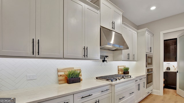 kitchen featuring stainless steel appliances, light wood finished floors, backsplash, and under cabinet range hood