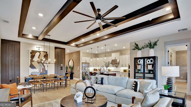 living room with brick wall, light wood-style flooring, visible vents, and beam ceiling