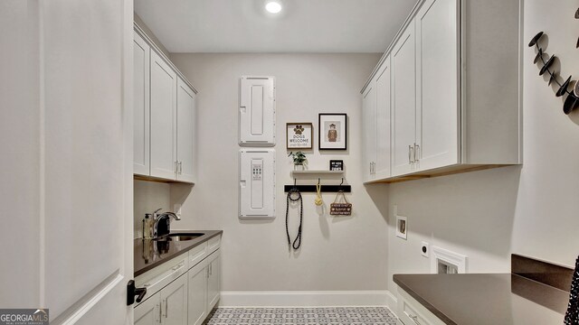 laundry room with cabinet space, baseboards, hookup for a washing machine, hookup for an electric dryer, and a sink