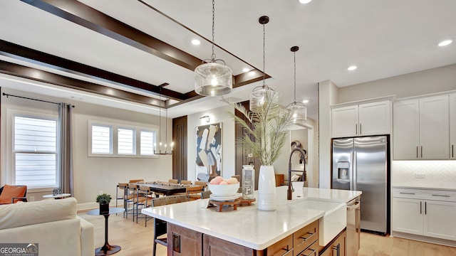 kitchen with open floor plan, light wood finished floors, backsplash, and stainless steel fridge