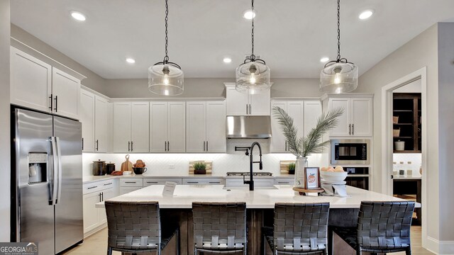 kitchen with white cabinetry, a kitchen breakfast bar, light countertops, appliances with stainless steel finishes, and decorative backsplash